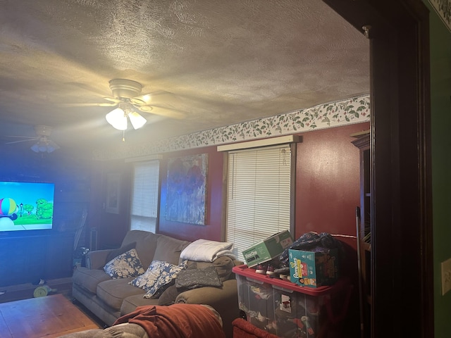 living room featuring ceiling fan and a textured ceiling