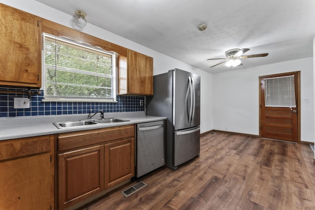 kitchen with decorative backsplash, appliances with stainless steel finishes, ceiling fan, sink, and dark hardwood / wood-style floors