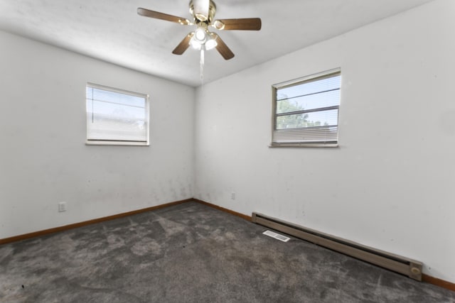 unfurnished room featuring ceiling fan, plenty of natural light, dark carpet, and a baseboard heating unit