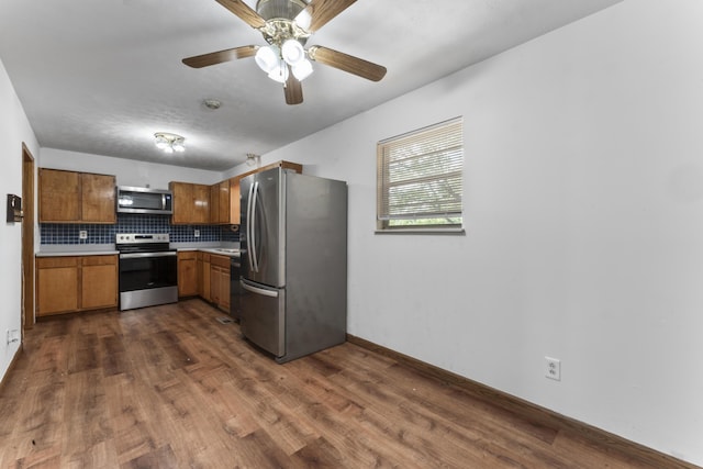 kitchen with tasteful backsplash, ceiling fan, dark wood-type flooring, and stainless steel appliances