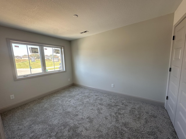 carpeted spare room featuring a textured ceiling