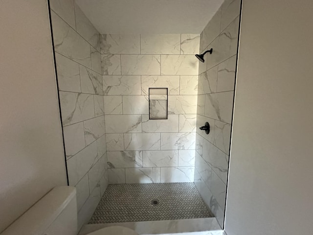 bathroom featuring toilet and a tile shower