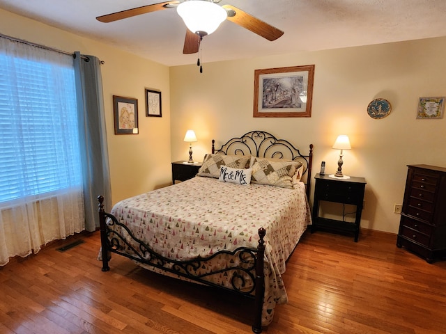 bedroom featuring wood-type flooring, visible vents, baseboards, and ceiling fan