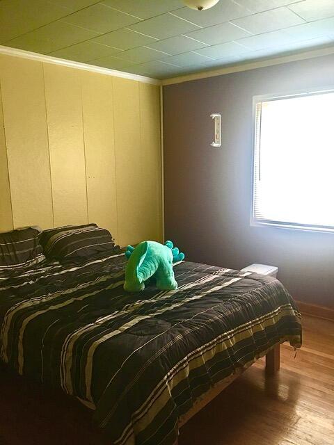 bedroom featuring crown molding and wood-type flooring