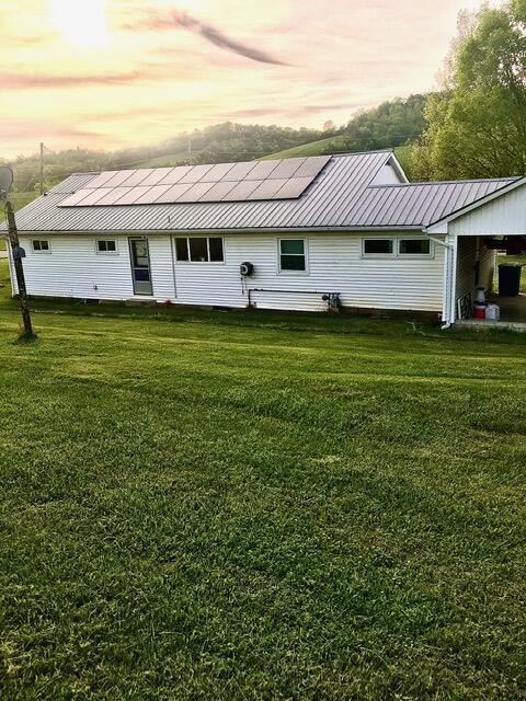 back house at dusk with a lawn and solar panels