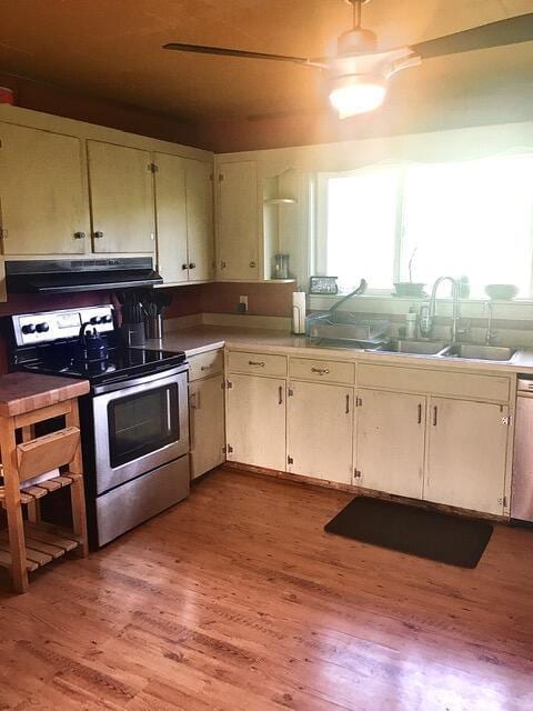 kitchen with stainless steel electric stove, a wealth of natural light, light hardwood / wood-style flooring, and range hood