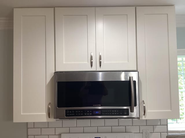 interior details featuring white cabinets and tasteful backsplash