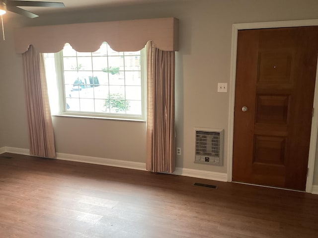 spare room featuring heating unit, ceiling fan, and hardwood / wood-style floors