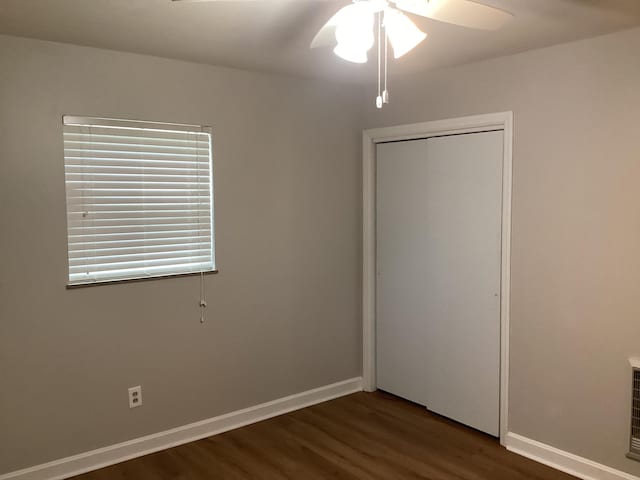 unfurnished bedroom with ceiling fan, a closet, and dark wood-type flooring