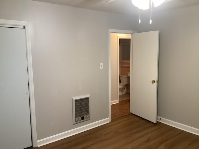 spare room with ceiling fan, dark wood-type flooring, and heating unit