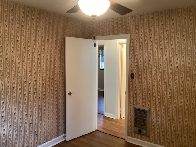 unfurnished room featuring heating unit, ceiling fan, and wood-type flooring