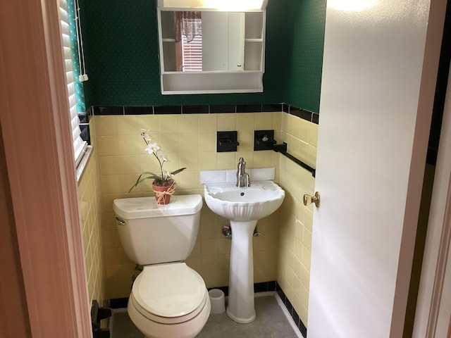 bathroom with tile patterned floors, toilet, and tile walls