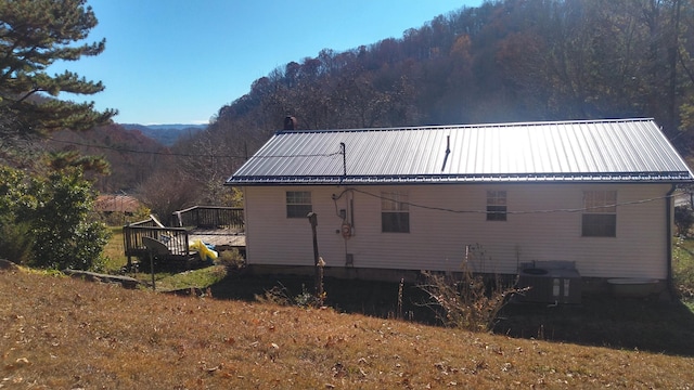 back of property with central AC unit and a wooden deck