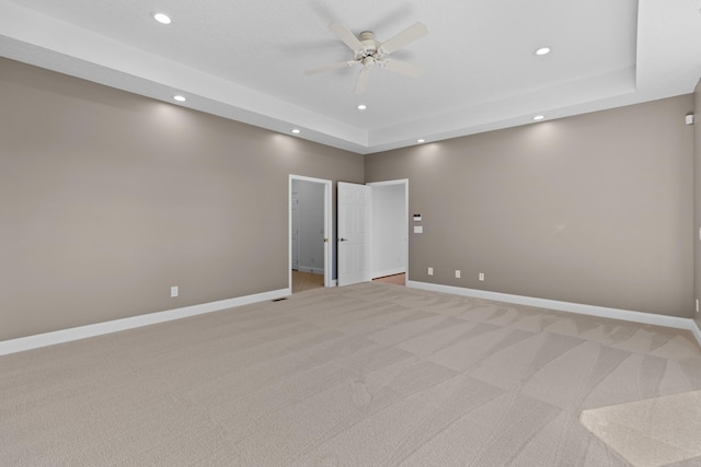 carpeted spare room featuring a raised ceiling and ceiling fan