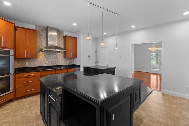 kitchen featuring wall chimney range hood, backsplash, a center island, black cooktop, and stainless steel double oven