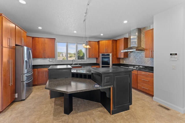 kitchen featuring a kitchen island, appliances with stainless steel finishes, sink, hanging light fixtures, and wall chimney range hood