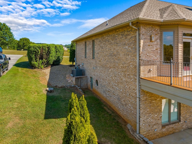 view of side of home with central AC unit and a lawn