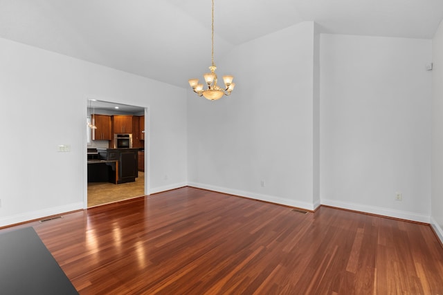 unfurnished room with hardwood / wood-style floors, vaulted ceiling, and a chandelier