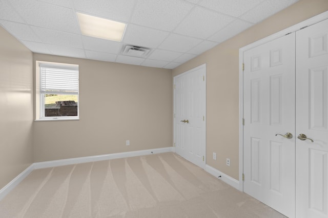 spare room featuring light colored carpet and a paneled ceiling