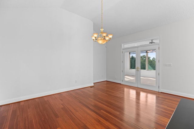 unfurnished room featuring hardwood / wood-style flooring, vaulted ceiling, an inviting chandelier, and french doors