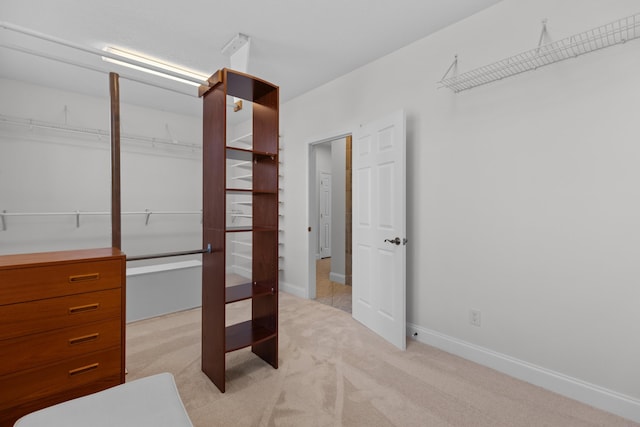 walk in closet featuring light colored carpet