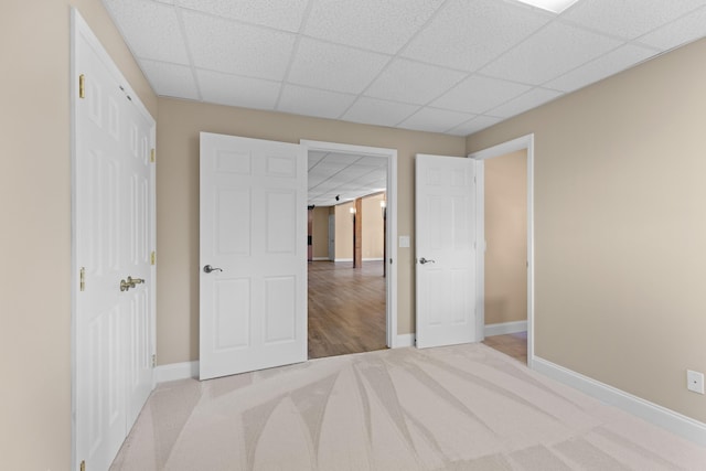 unfurnished bedroom with a paneled ceiling and light colored carpet