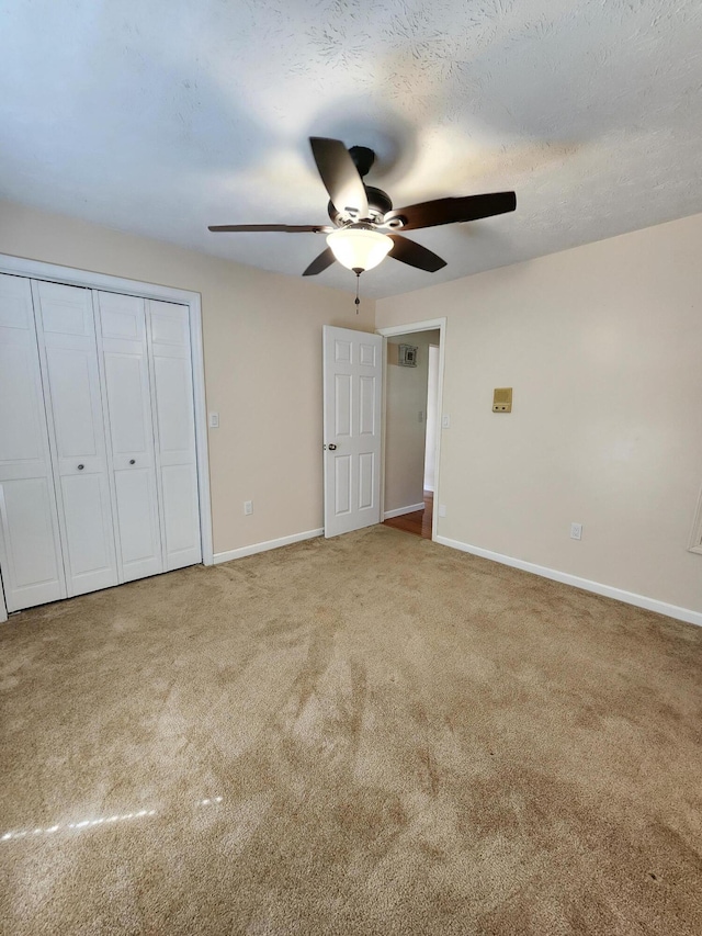 unfurnished bedroom with carpet flooring, ceiling fan, a closet, and a textured ceiling