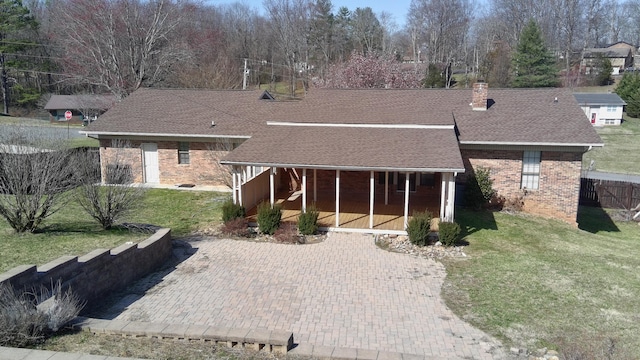 view of front of property featuring fence, a shingled roof, a chimney, a front lawn, and brick siding