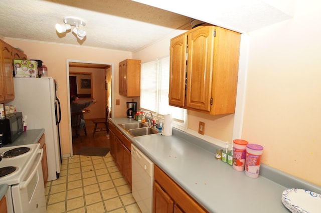 kitchen with a sink, white appliances, a textured ceiling, and light countertops