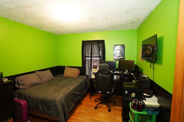 bedroom with a textured ceiling and wood finished floors