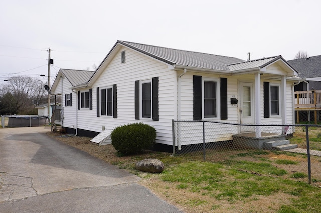 view of front of home featuring a porch, metal roof, and fence