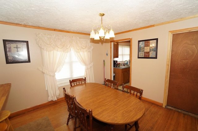 dining space featuring a textured ceiling, an inviting chandelier, wood finished floors, and crown molding