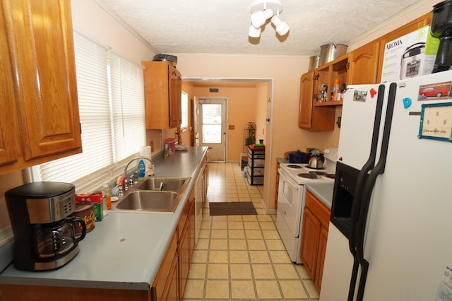 kitchen with white appliances, light tile patterned floors, a sink, a textured ceiling, and brown cabinets