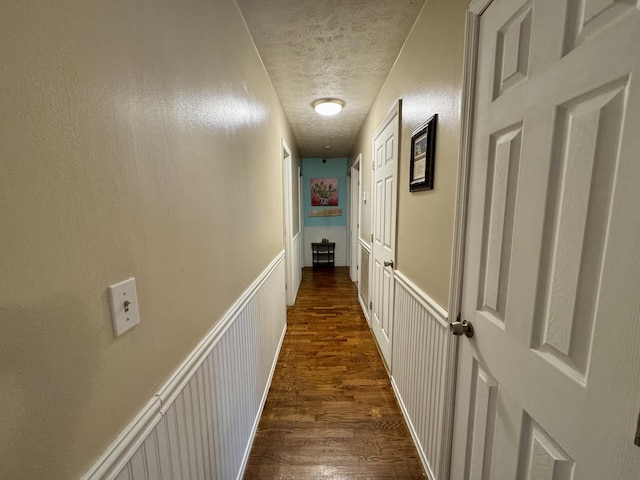 corridor featuring a textured ceiling and dark wood-type flooring