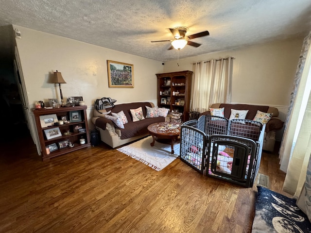 living room with ceiling fan, a textured ceiling, and hardwood / wood-style flooring