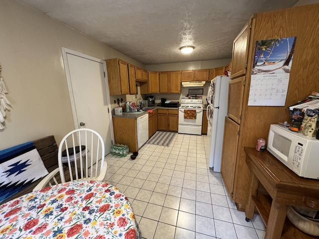 kitchen with a textured ceiling, sink, light tile patterned floors, and white appliances