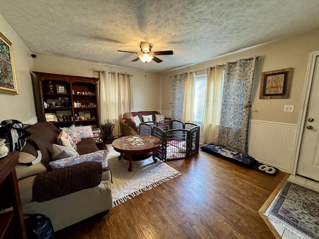 living room featuring ceiling fan, wood-type flooring, and a textured ceiling