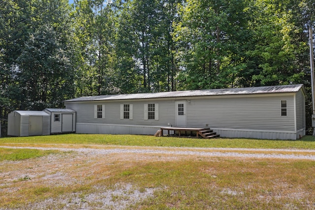 back of house with a storage unit, a lawn, metal roof, and an outbuilding
