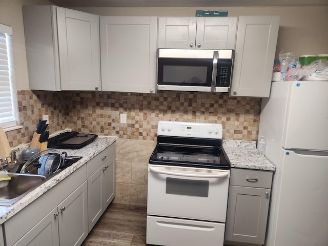 kitchen featuring light stone countertops, sink, white appliances, and decorative backsplash