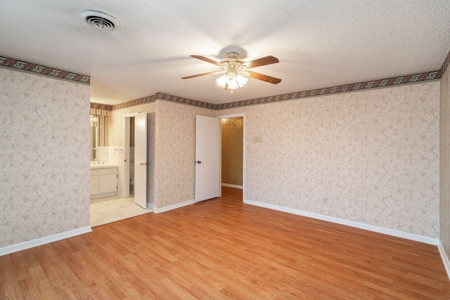 unfurnished bedroom with connected bathroom, hardwood / wood-style floors, and a textured ceiling