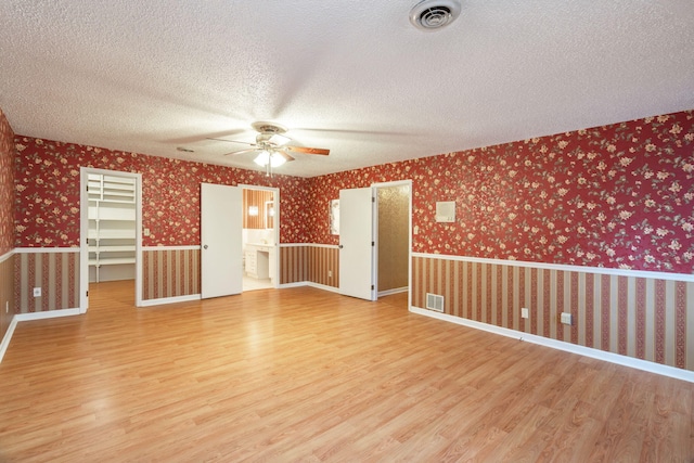 empty room featuring ceiling fan, hardwood / wood-style floors, and a textured ceiling