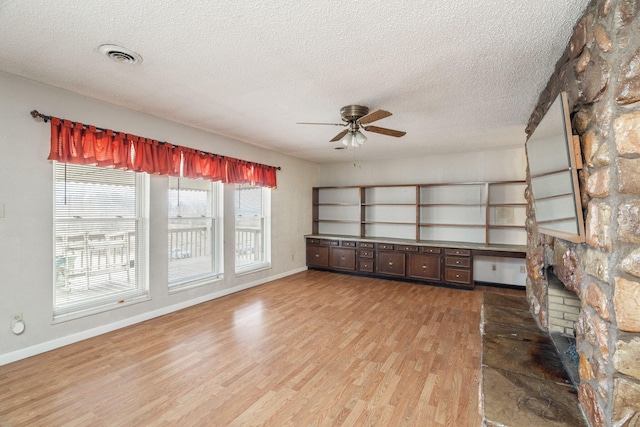 unfurnished living room featuring ceiling fan, a textured ceiling, and light wood-type flooring