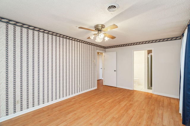 unfurnished bedroom with ceiling fan, connected bathroom, hardwood / wood-style floors, and a textured ceiling