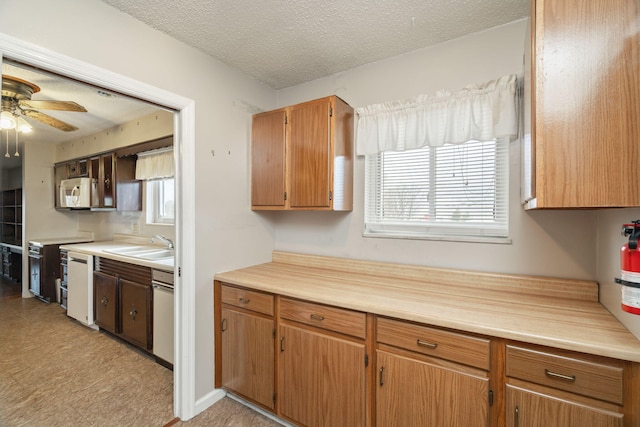 kitchen featuring sink, stove, stainless steel dishwasher, ceiling fan, and a textured ceiling