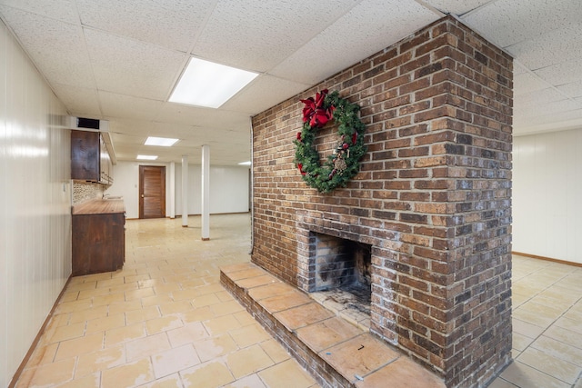 unfurnished living room with light tile patterned floors, a fireplace, and a paneled ceiling