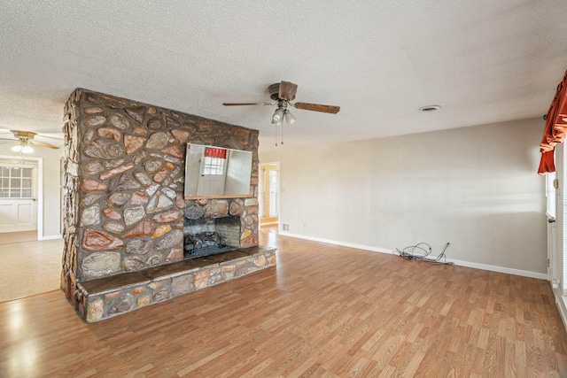 unfurnished living room with wood-type flooring, a textured ceiling, ceiling fan, and a fireplace