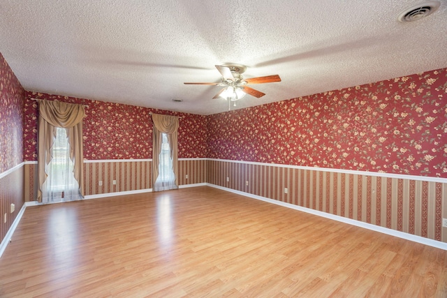 unfurnished room featuring a wealth of natural light, wood-type flooring, and a textured ceiling