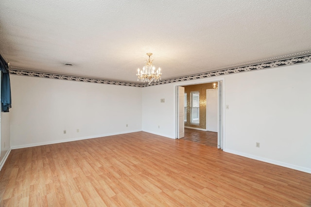 spare room with hardwood / wood-style flooring, a notable chandelier, and a textured ceiling