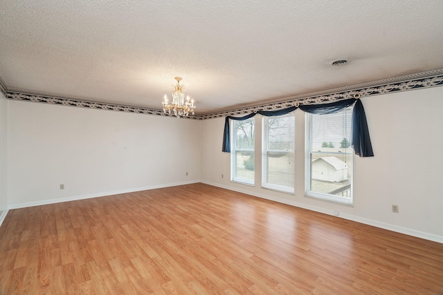 spare room with hardwood / wood-style floors, a textured ceiling, and a chandelier