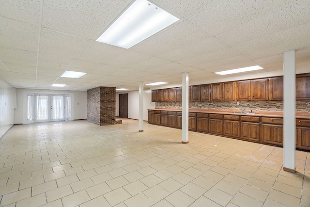 basement featuring sink, a drop ceiling, and french doors